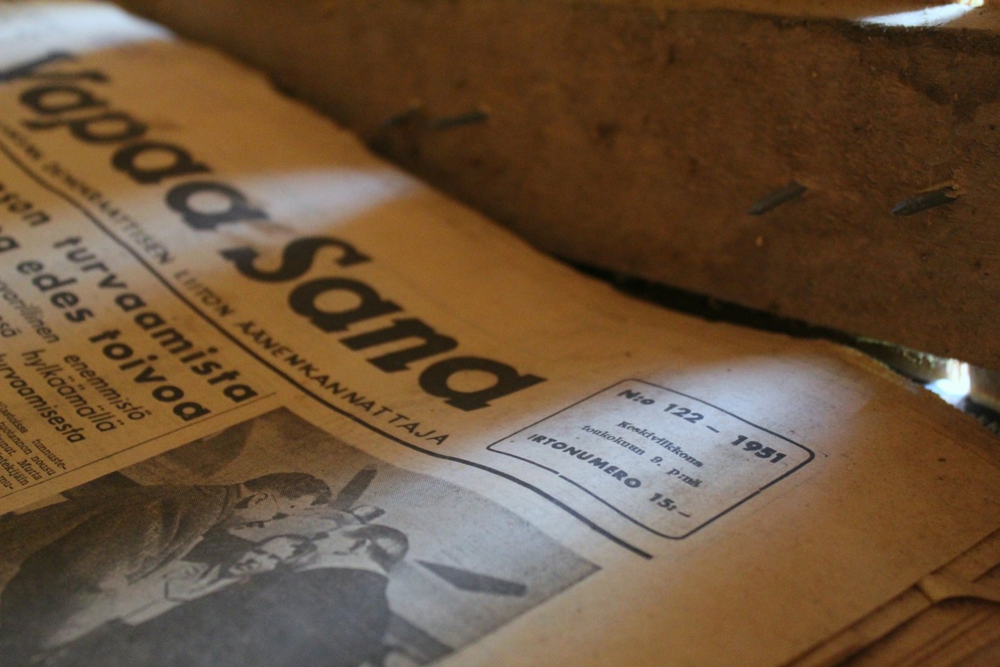 Yellowed newspaper with headlines lies open on wood.