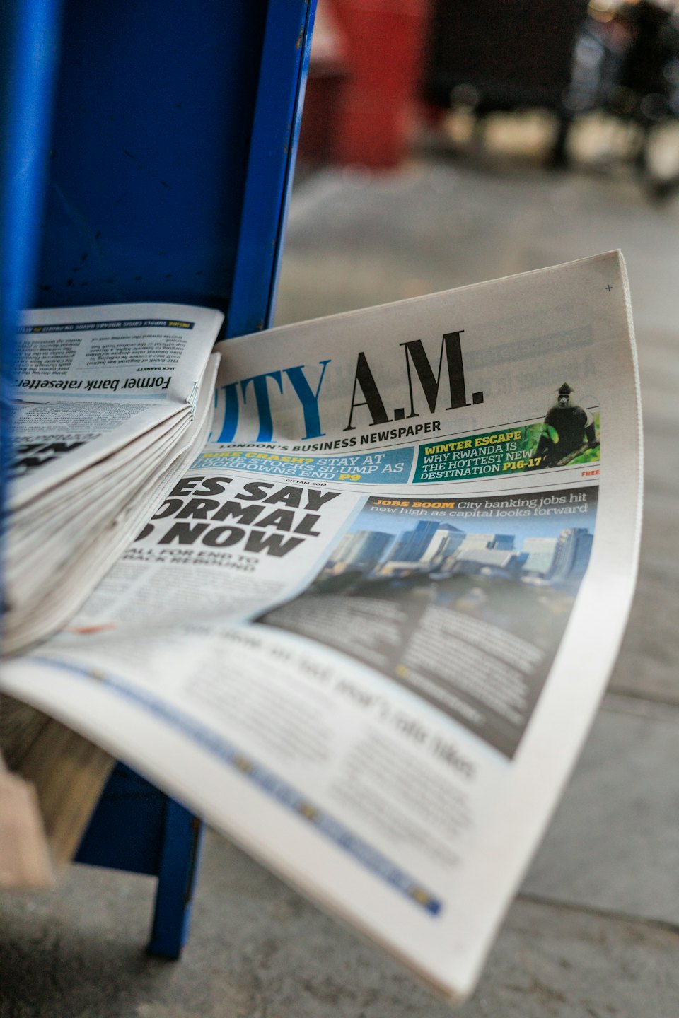 City A.M. business newspaper displayed in a blue metal stand.