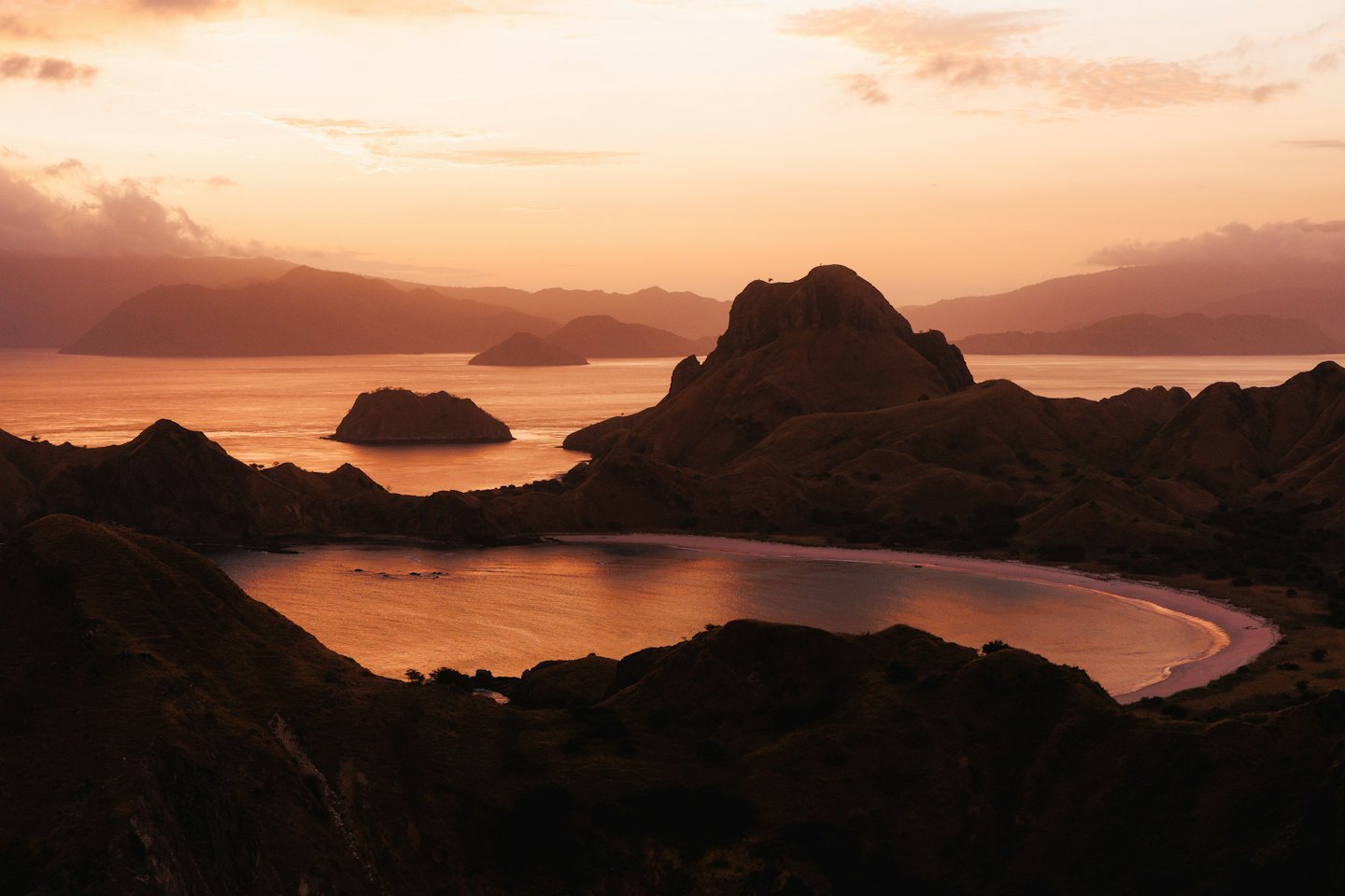 Islands and hills silhouetted against a colorful sunrise sky over the bay.